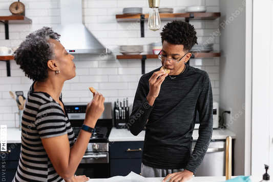 Black mother and son enjoying fresh baked homemade cookies in kitchen