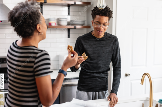 Black mother and son enjoying fresh baked homemade cookies in kitchen