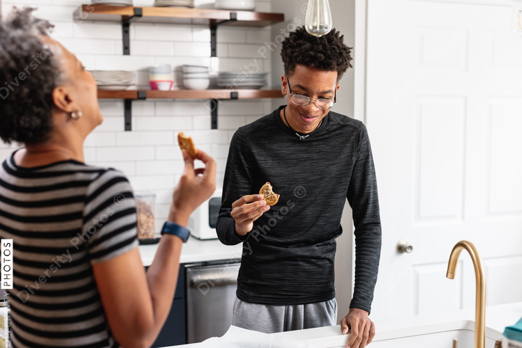 Black mother and son enjoying fresh baked homemade cookies in kitchen