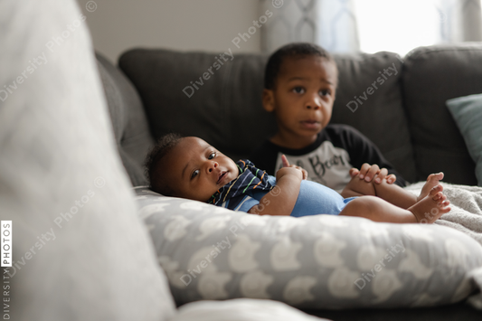 Black boys, siblings, sitting and laying on sofa