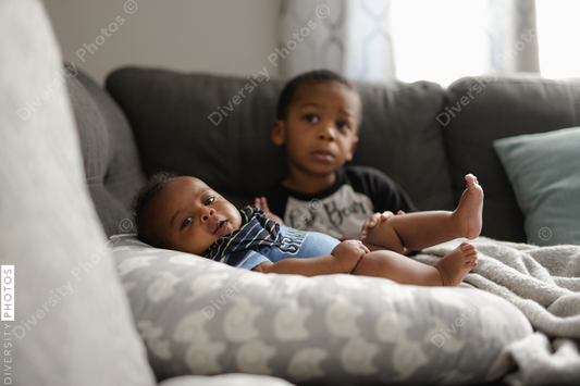 Black boys, siblings, sitting and laying on sofa