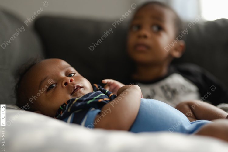 Black boys, siblings, sitting and laying on sofa
