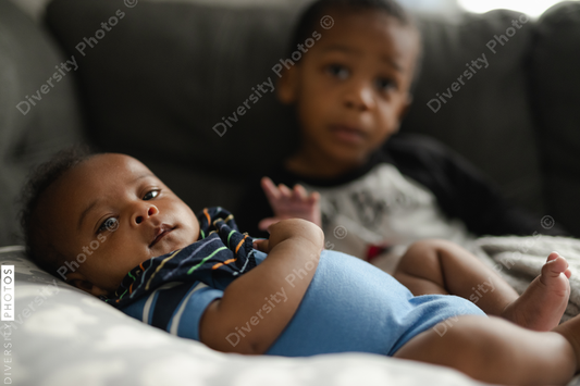 Black boys, siblings, sitting and laying on sofa
