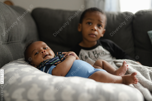 Black boys, siblings, sitting and laying on sofa