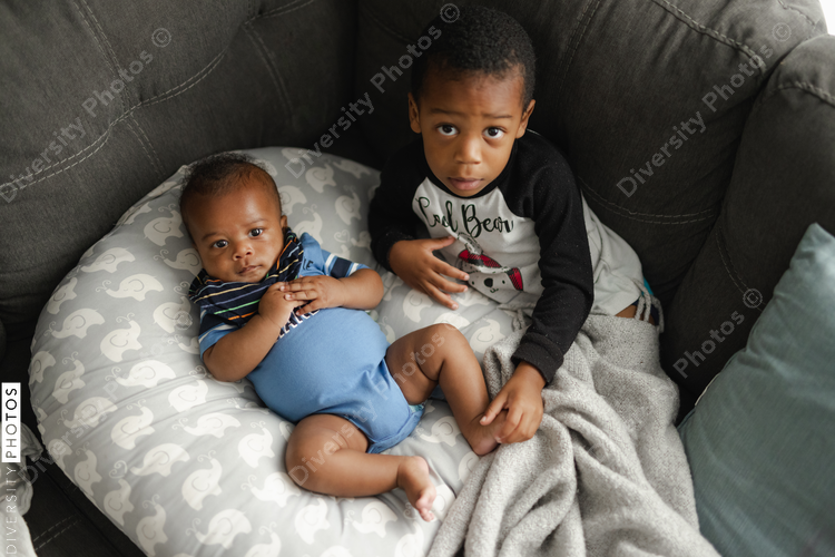 Black boys, siblings, sitting and laying on sofa