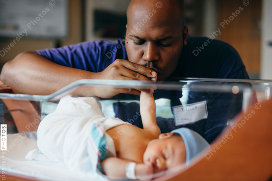 Black dad kisses newborn at hospital
