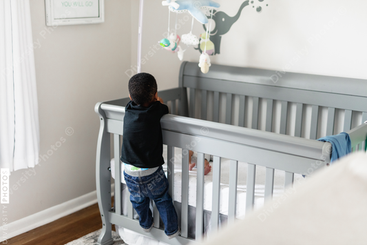 Big brother checking on sibling in crib, crying baby