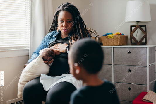 Black mom breastfeeds baby and talks to sibling