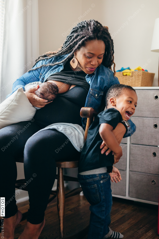 Black mom breastfeeds baby and talks to sibling