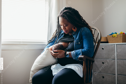 Black woman breastfeeding child at home