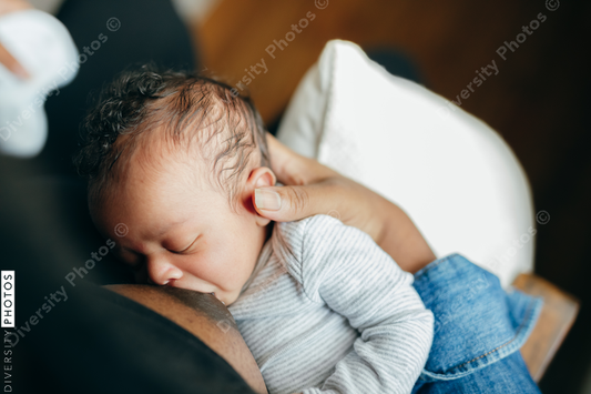 Black woman breastfeeding child at home