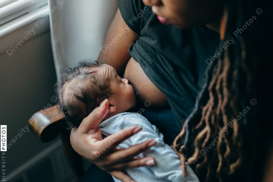 Black woman breastfeeding child at home