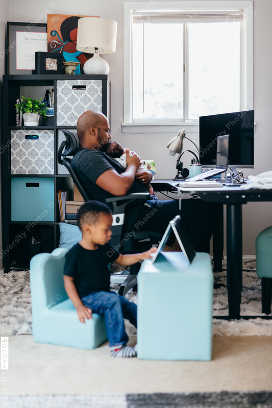 Black dad with newborn working from home