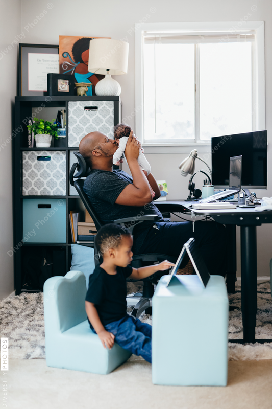 Black dad with newborn working from home
