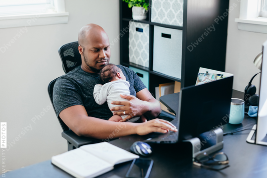 Black dad with newborn working from home