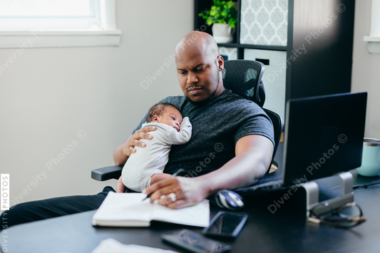 Black dad with newborn working from home