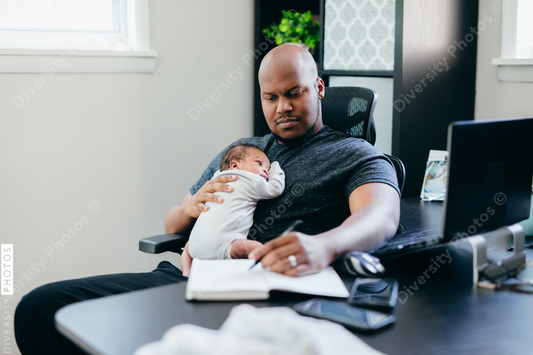 Black dad with newborn working from home