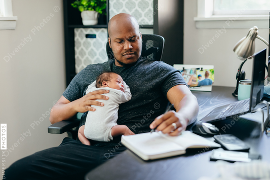 Black dad with newborn working from home
