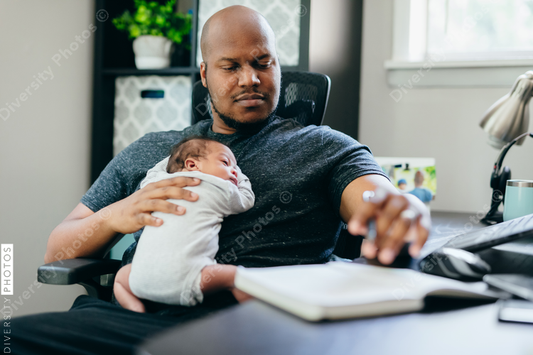 Black dad with newborn working from home