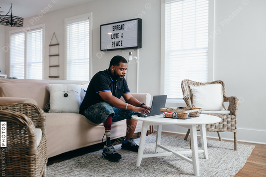 Black man with prosthetic leg working from home on laptop