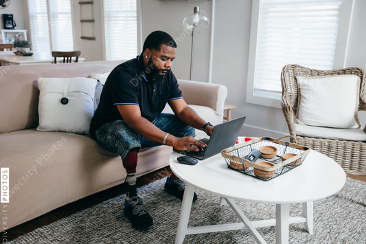 Black man with prosthetic leg working from home on laptop