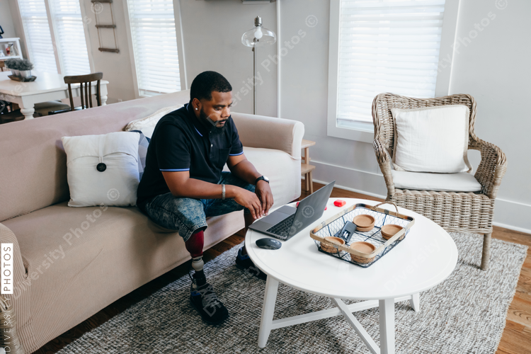 Black man with prosthetic leg working from home on laptop