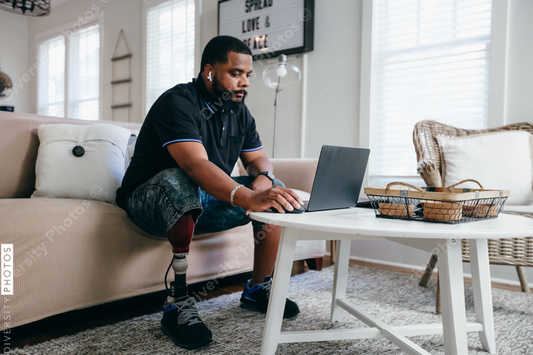 Black man with prosthetic leg working from home on laptop