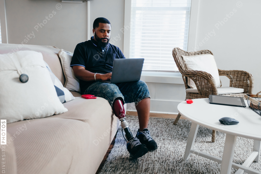 Black man with prosthetic leg working from home on laptop