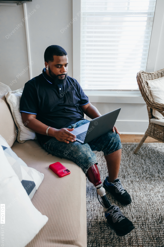 African American man working from home on laptop, disability 
