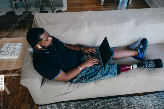 African American man working from home on laptop, disability 
