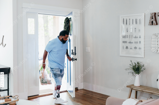 Black man with prosthetic leg bringing home groceries