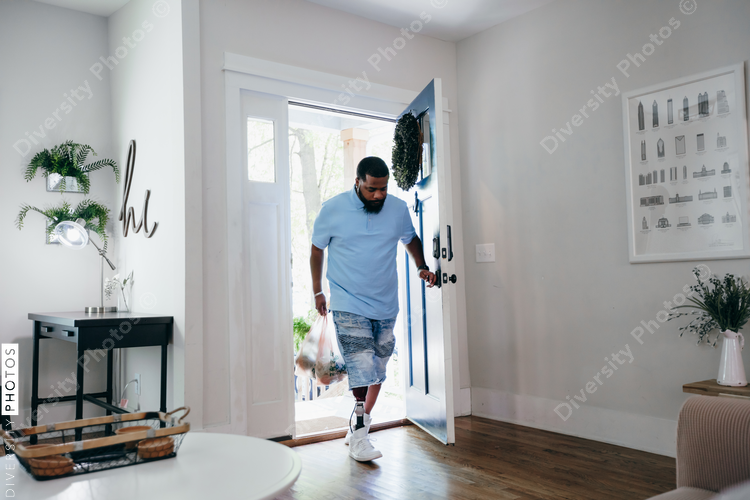 Black man with prosthetic leg bringing home groceries