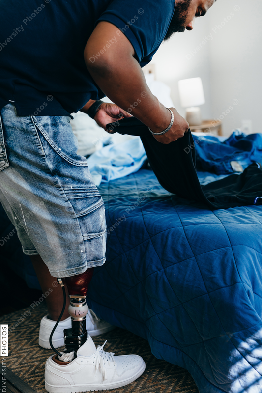 African American man with prosthetic leg doing chores, laundry, at home