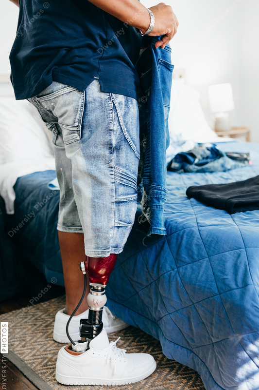 African American man with prosthetic leg doing chores, laundry, at home