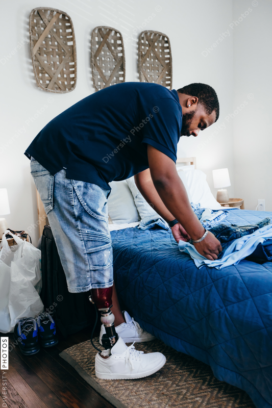 African American man with prosthetic leg doing chores, laundry, at home