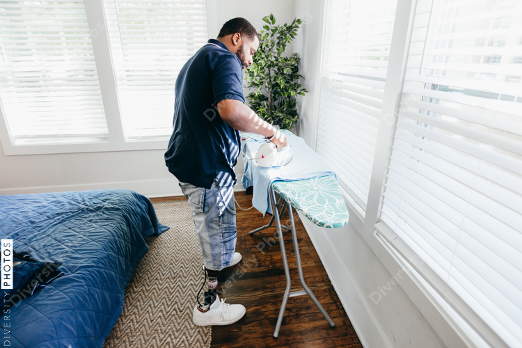 Black man ironing clothes, everyday life, disabled