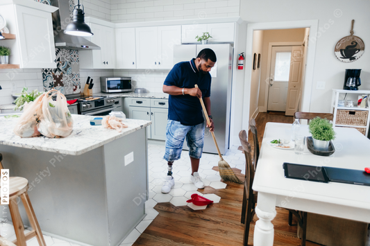 African American man doing chores around the house, sweeping, disabled