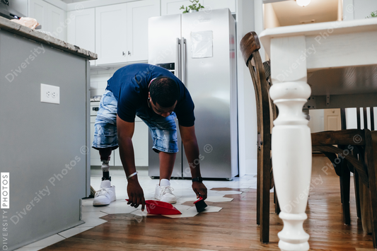 African American man doing chores around the house, sweeping, disabled