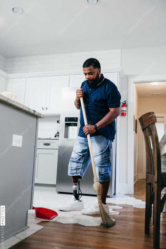 African American man doing chores around the house, sweeping, disabled