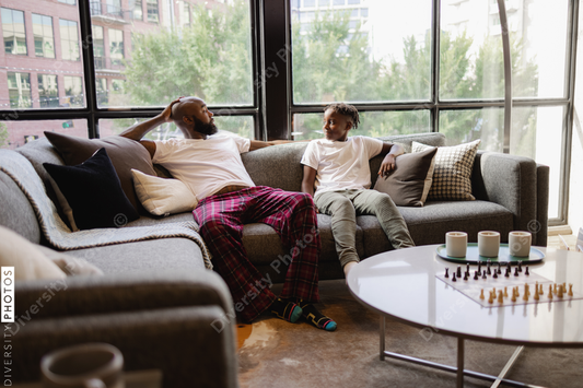 Black Father and son sitting on sofa in living room talking