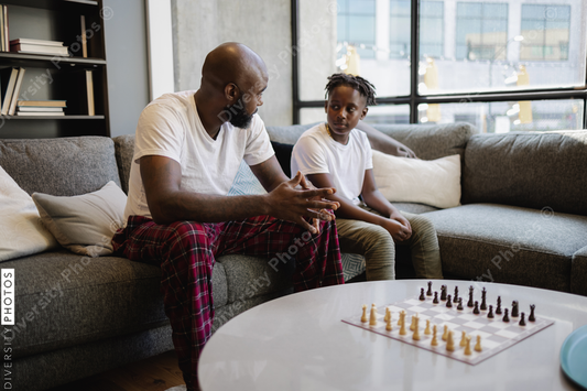Black Father and son sitting on sofa in living room