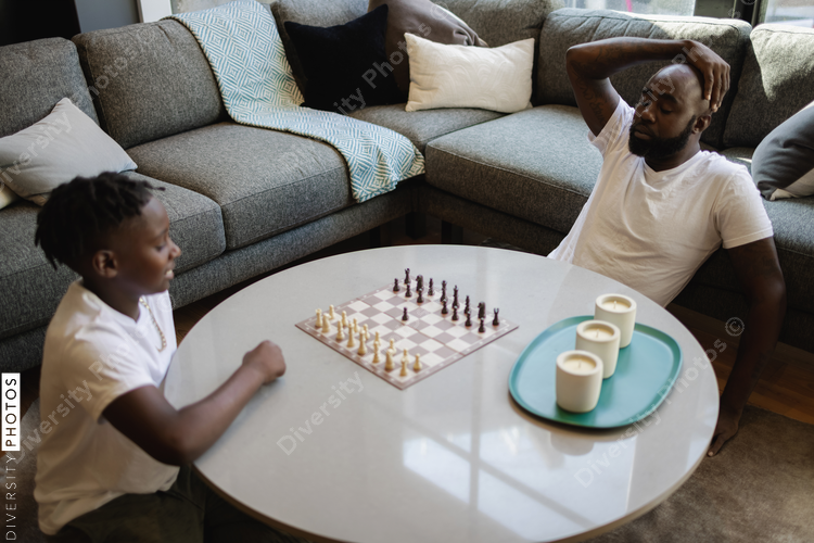 Father and son playing chess in living room