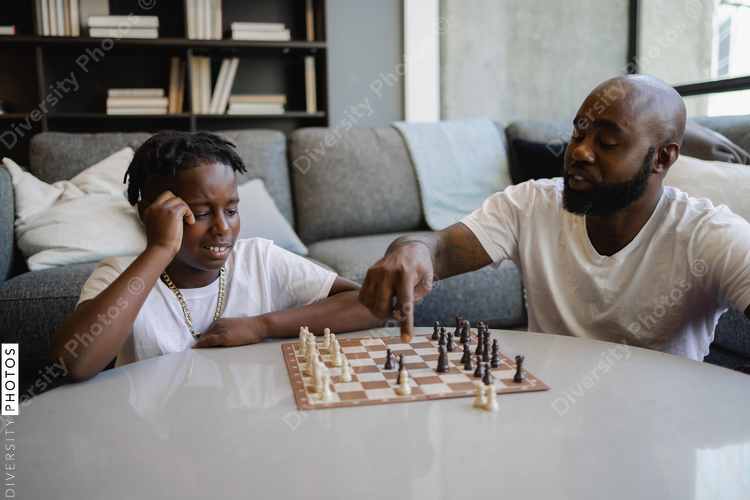 African American Father and son playing chess in living room