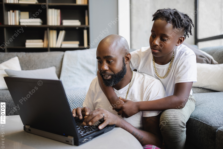 Father and son looking at laptop in living room