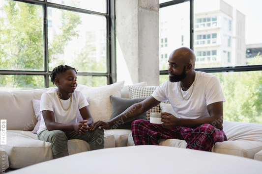 Black Father and son sitting on sofa in living room
