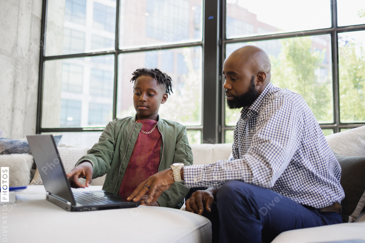 Black dad working from home with son
