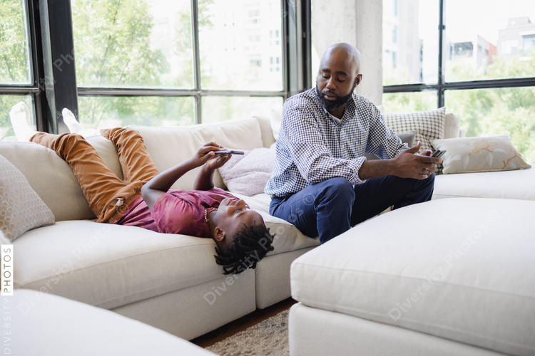 Father and son using smart phones on sofa
