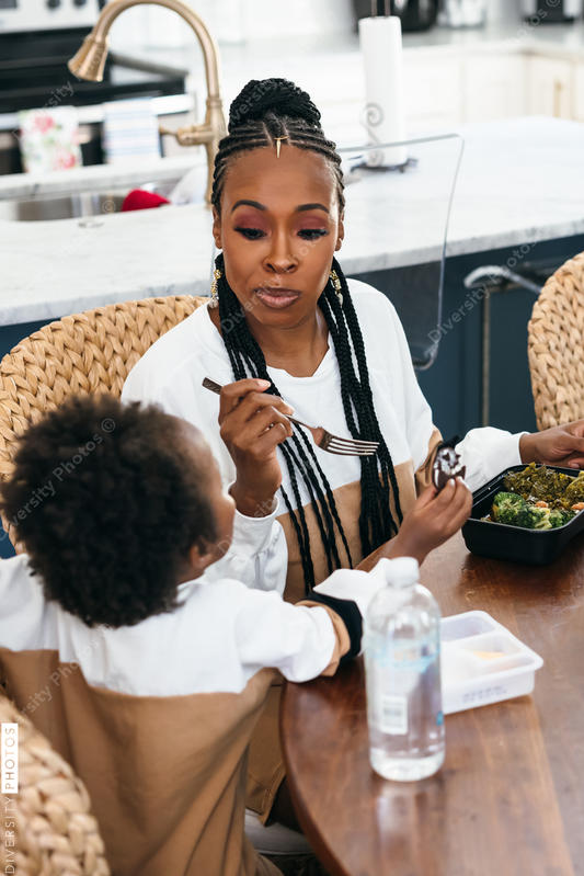 Black stay at home mother eats lunch with son and daughter