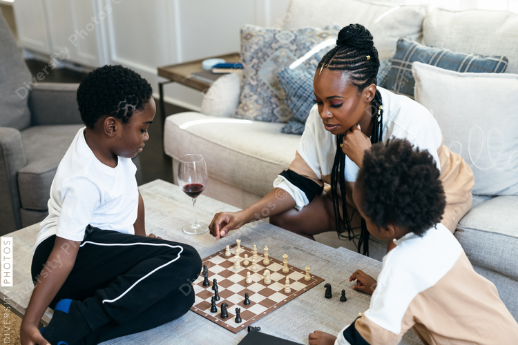 African American mother, daughter, and son playing chess at home