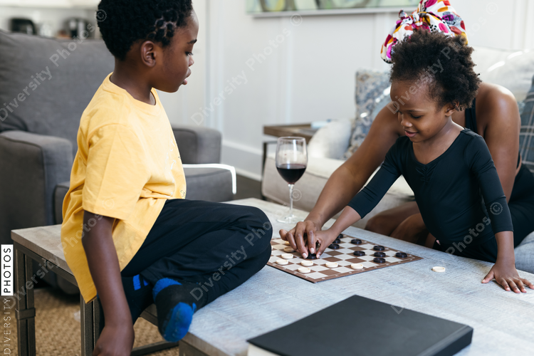 African American family playing checkers game at home